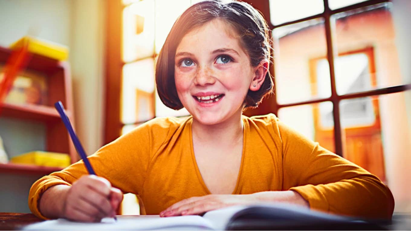 Grade school aged girl writing in notebook, happy because her parents made personal sacrifices