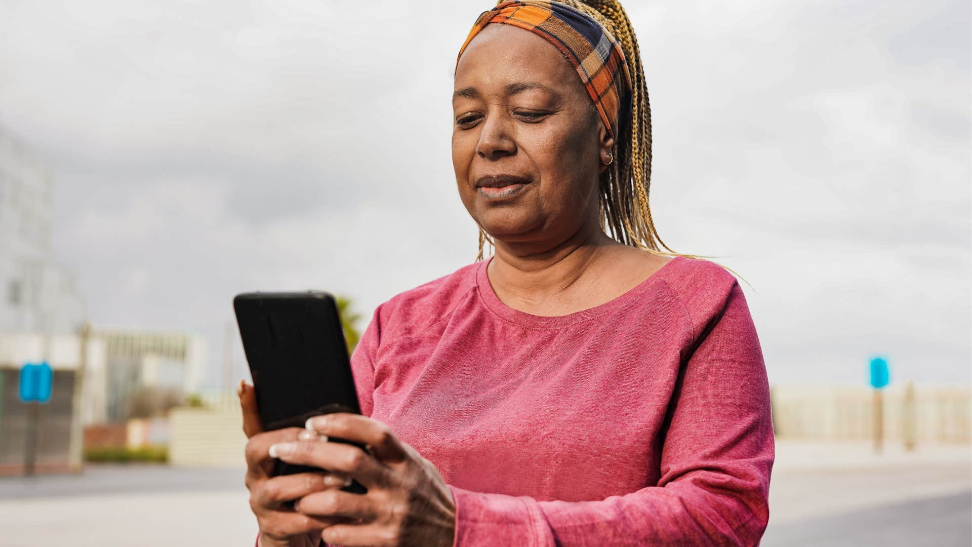 older woman texting on her phone outside