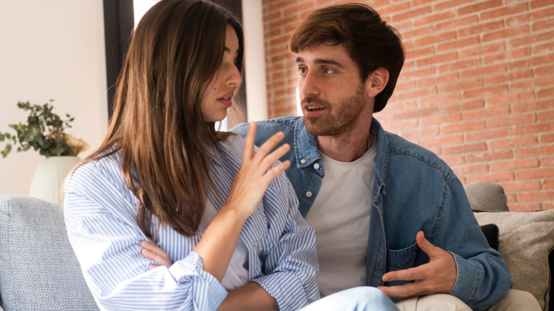 Woman holding her hand up in her upset husband's face.