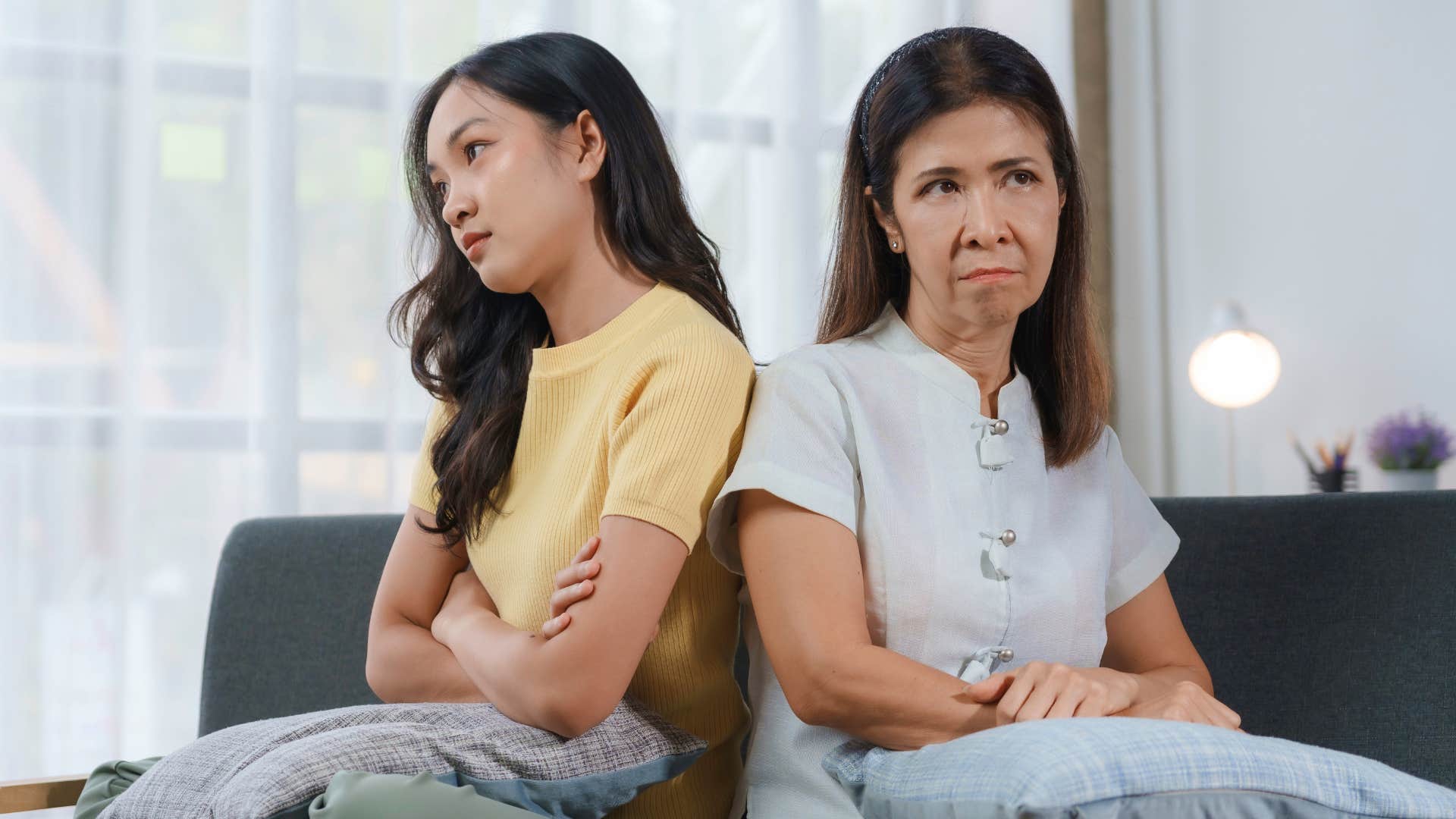 woman and mother sitting back to back