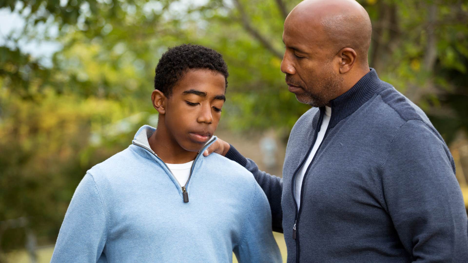 upset man holding son's shoulder