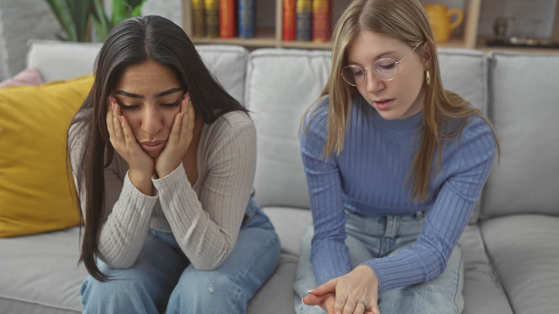 woman sitting next to friend to comfort her