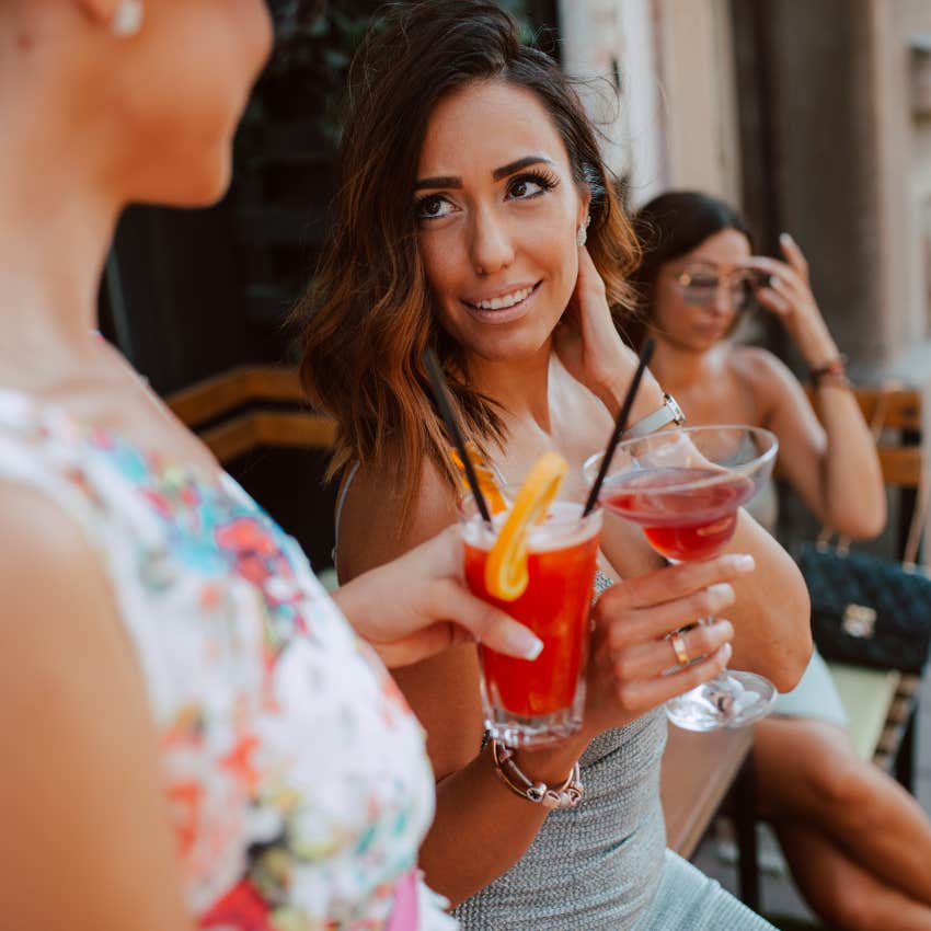 woman with brown hair speaking with her friend over drinks