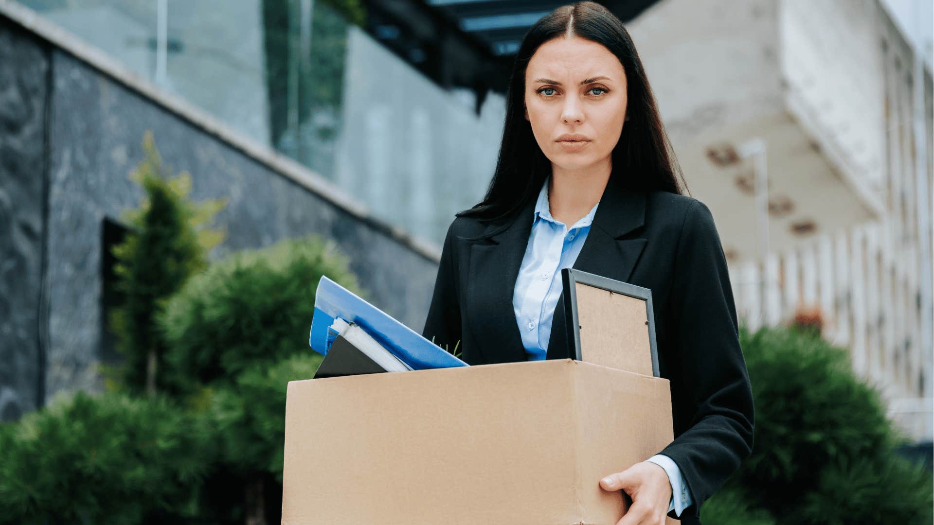 woman holding box of her belongings leaving work