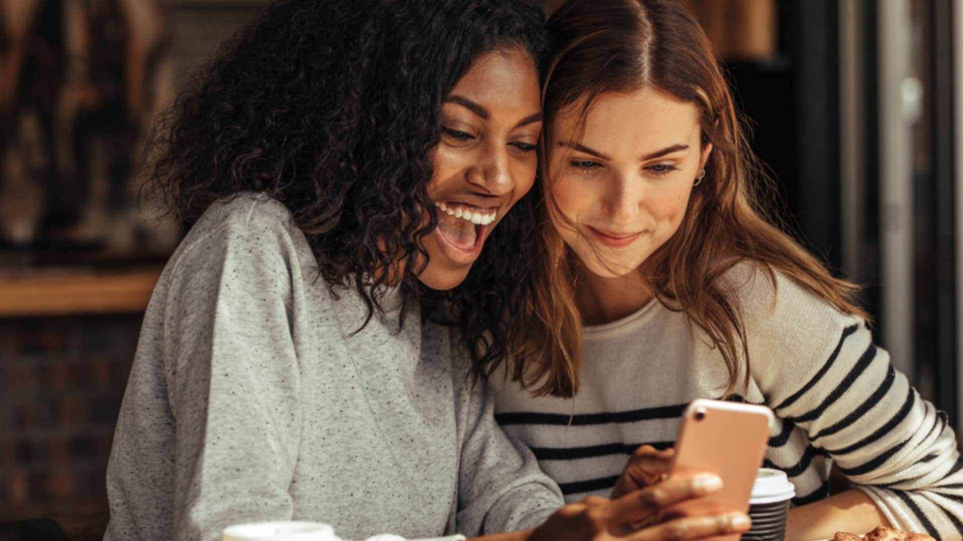 two friends smiling while looking at phone