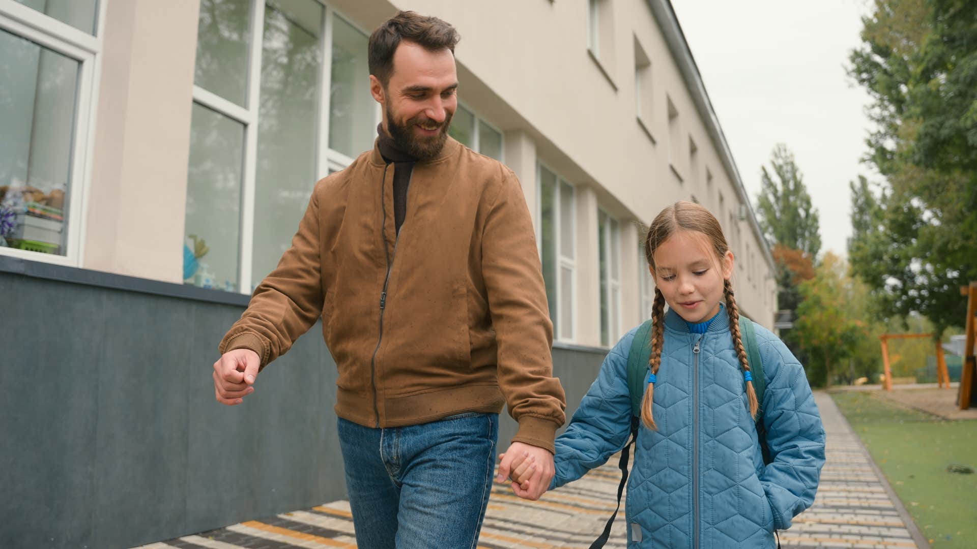 dad holding hands with daughter walking down street