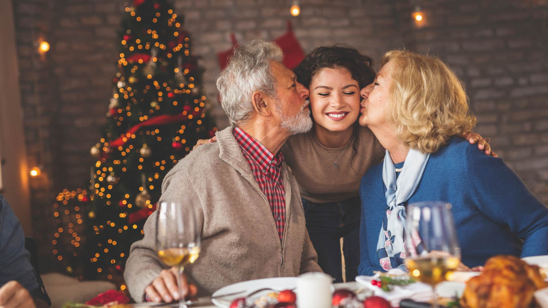 parents kissing their daughter's cheek at dinner