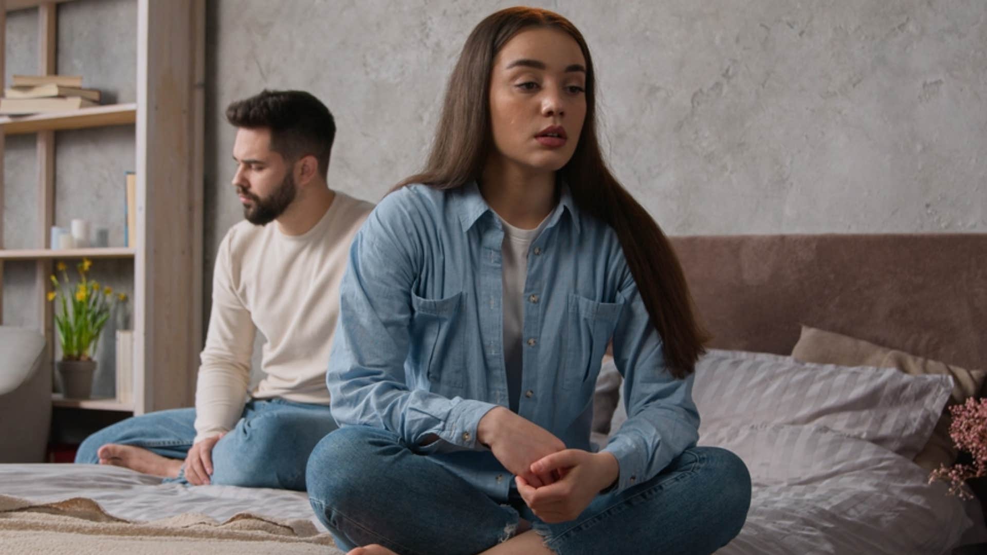 anxious woman sitting in bed with partner