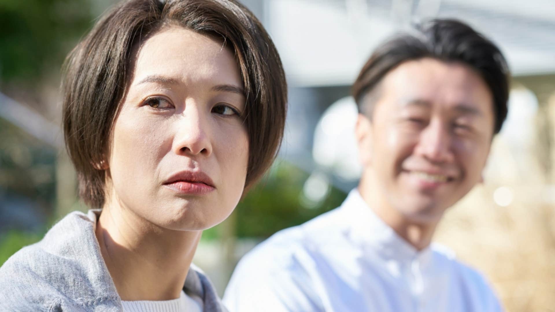 sad woman turned away from smiling man