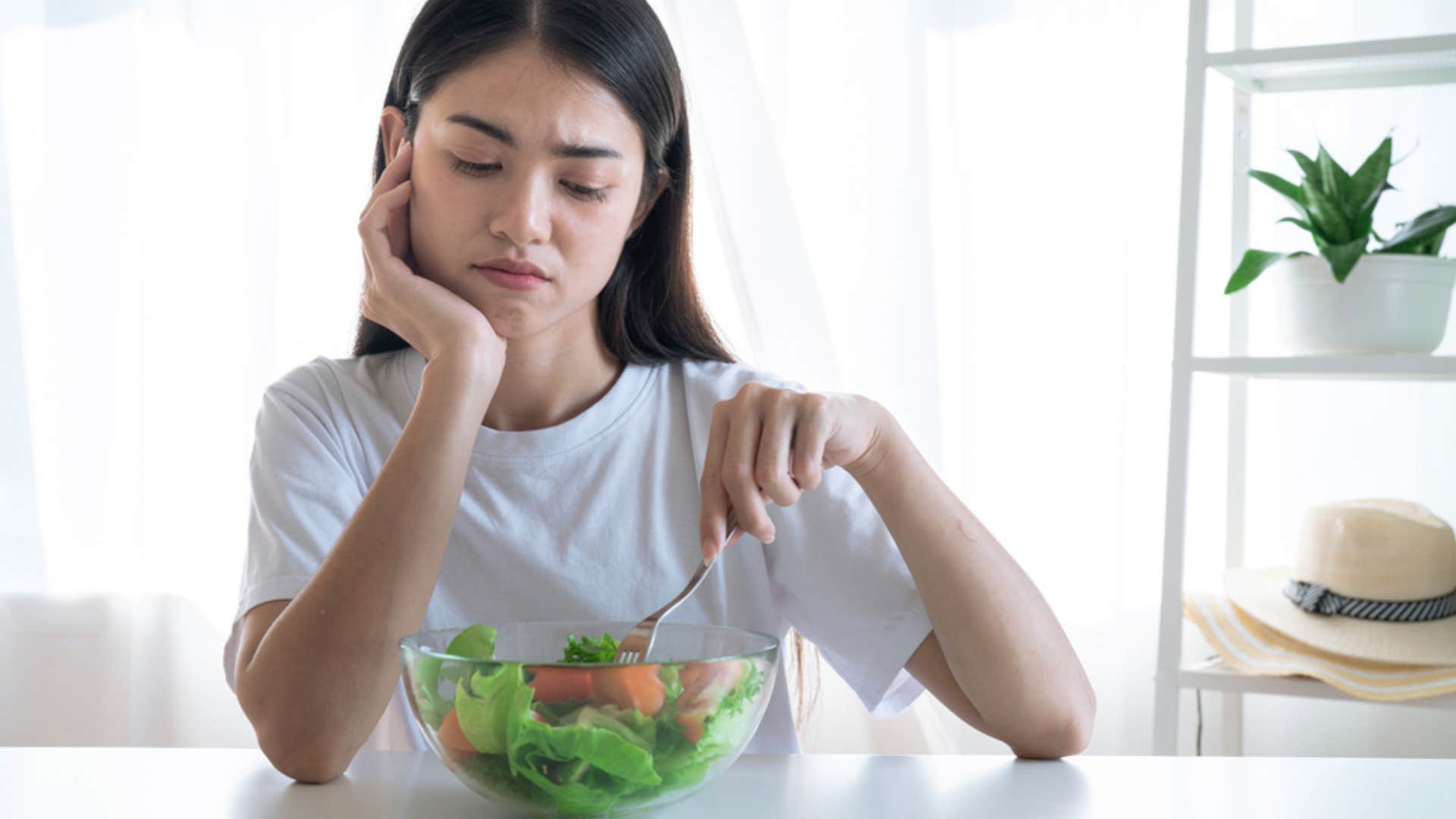 woman picking at salad uninterested in eating