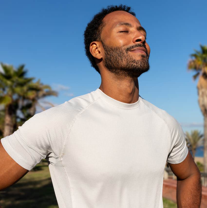 Relaxed man takes deep breath outside 