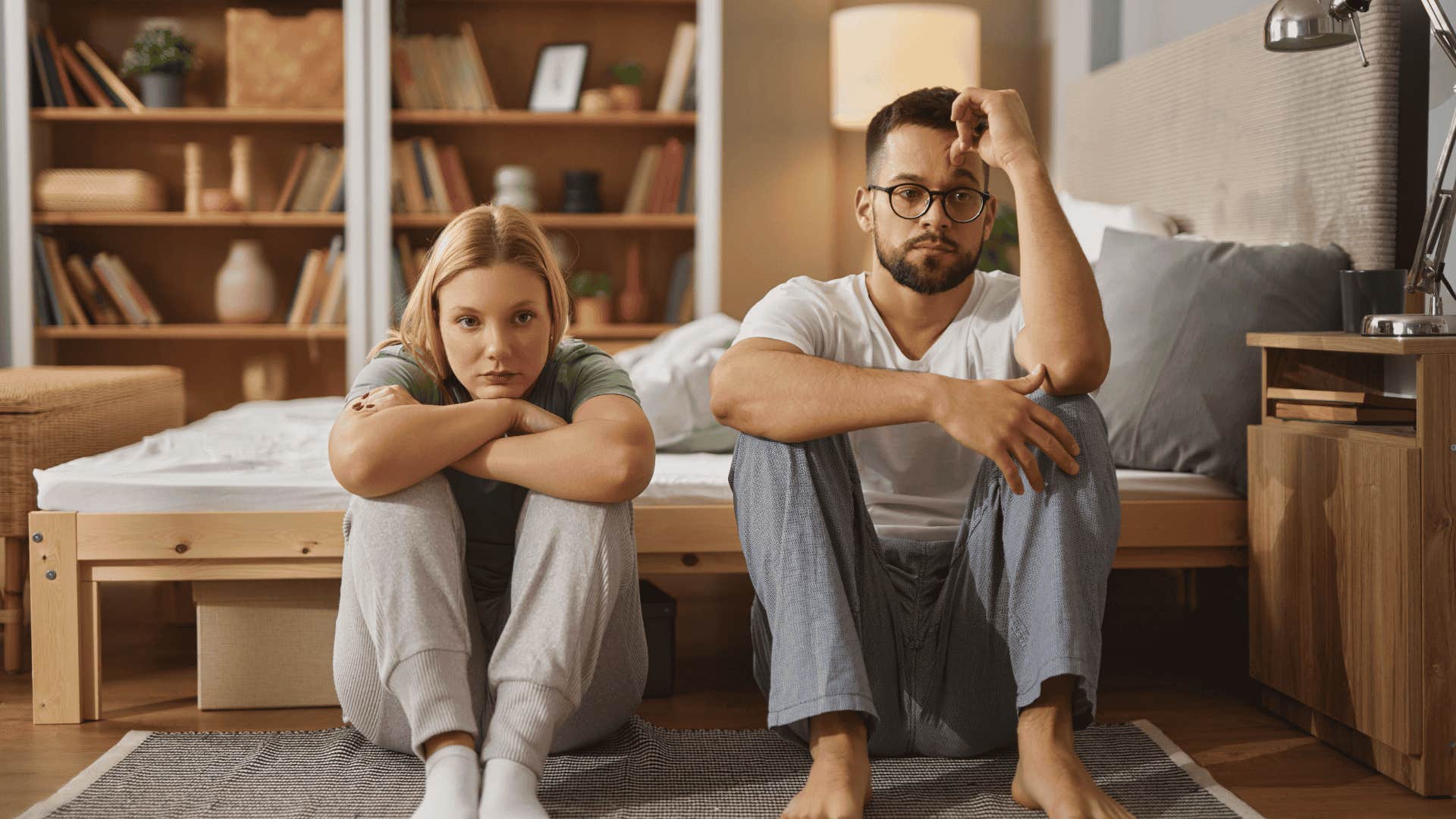 couple sitting next to each other on floor not supporting each other's dreams