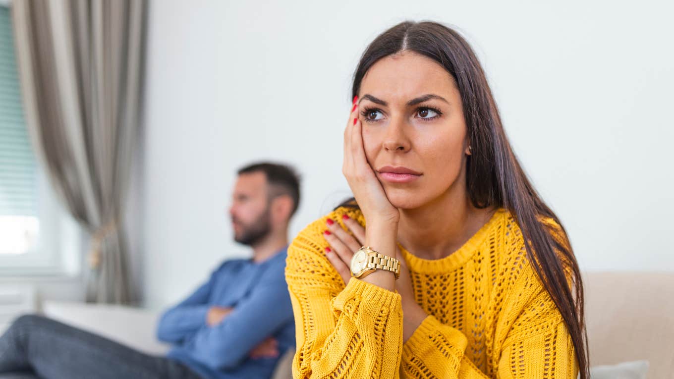 unhappy wife with husband ignored in background