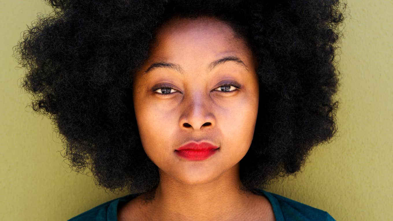 Woman with natural Black hair looks into camera, wondering what keeps her from life of her dreams