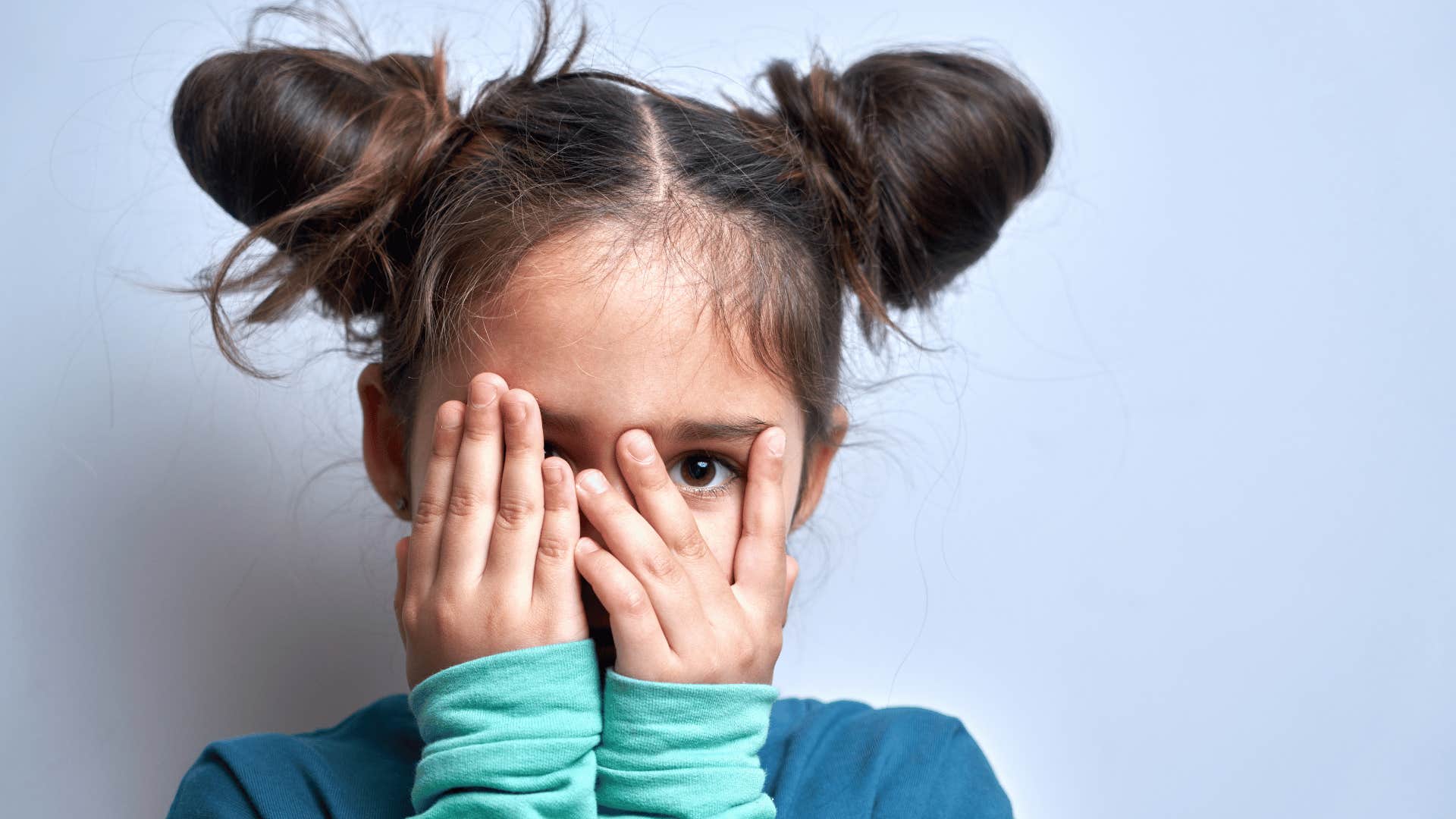 child with her hands on her face