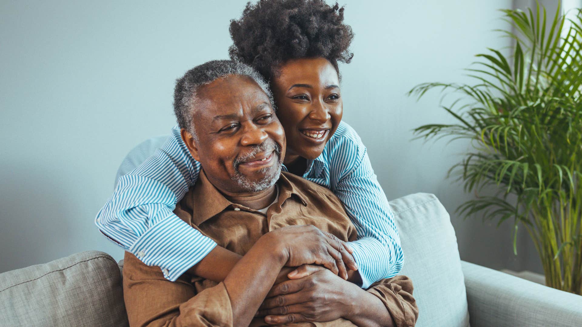 young woman hugging her grandfather from behind