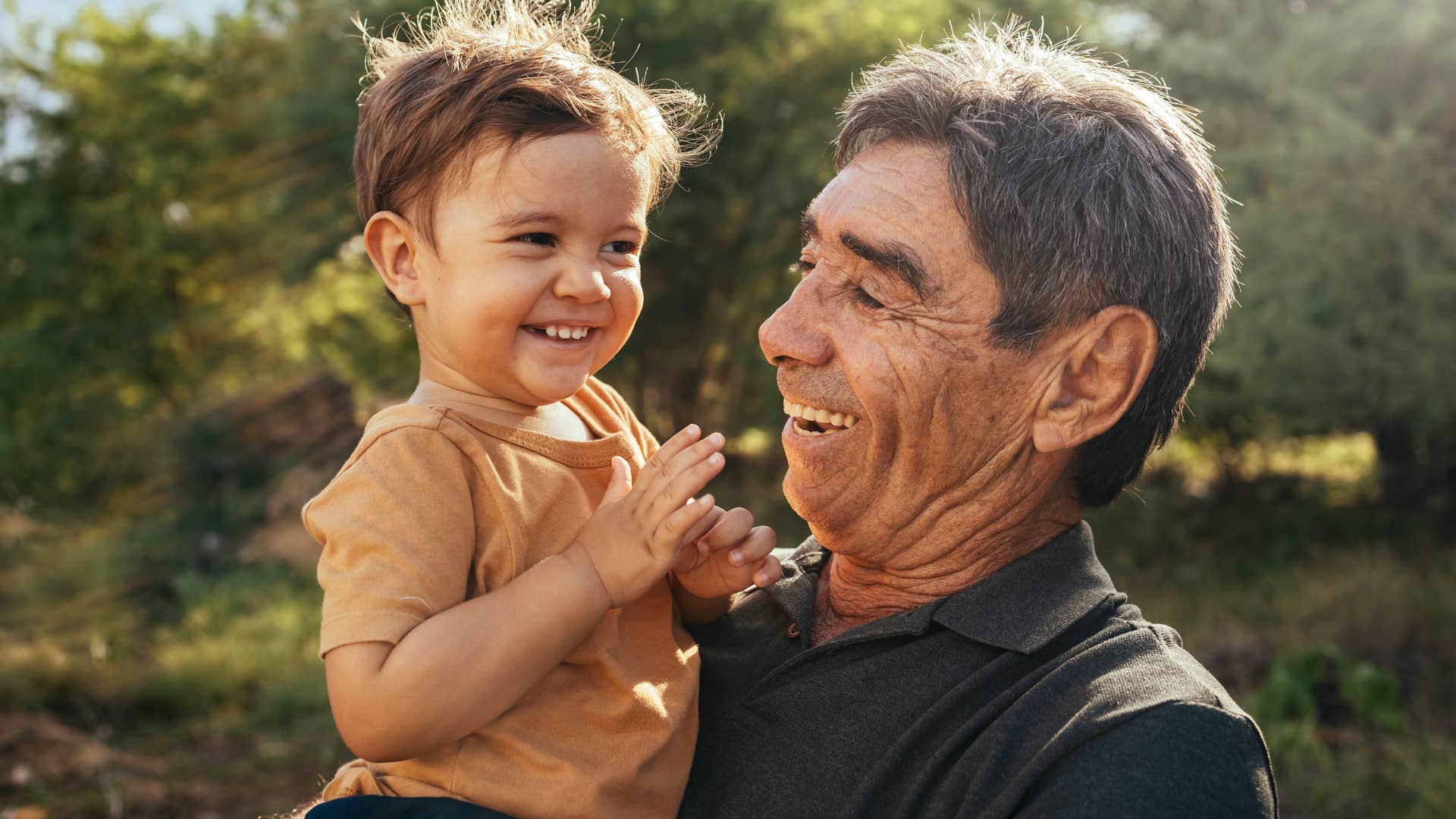 older man smiling and holding young child