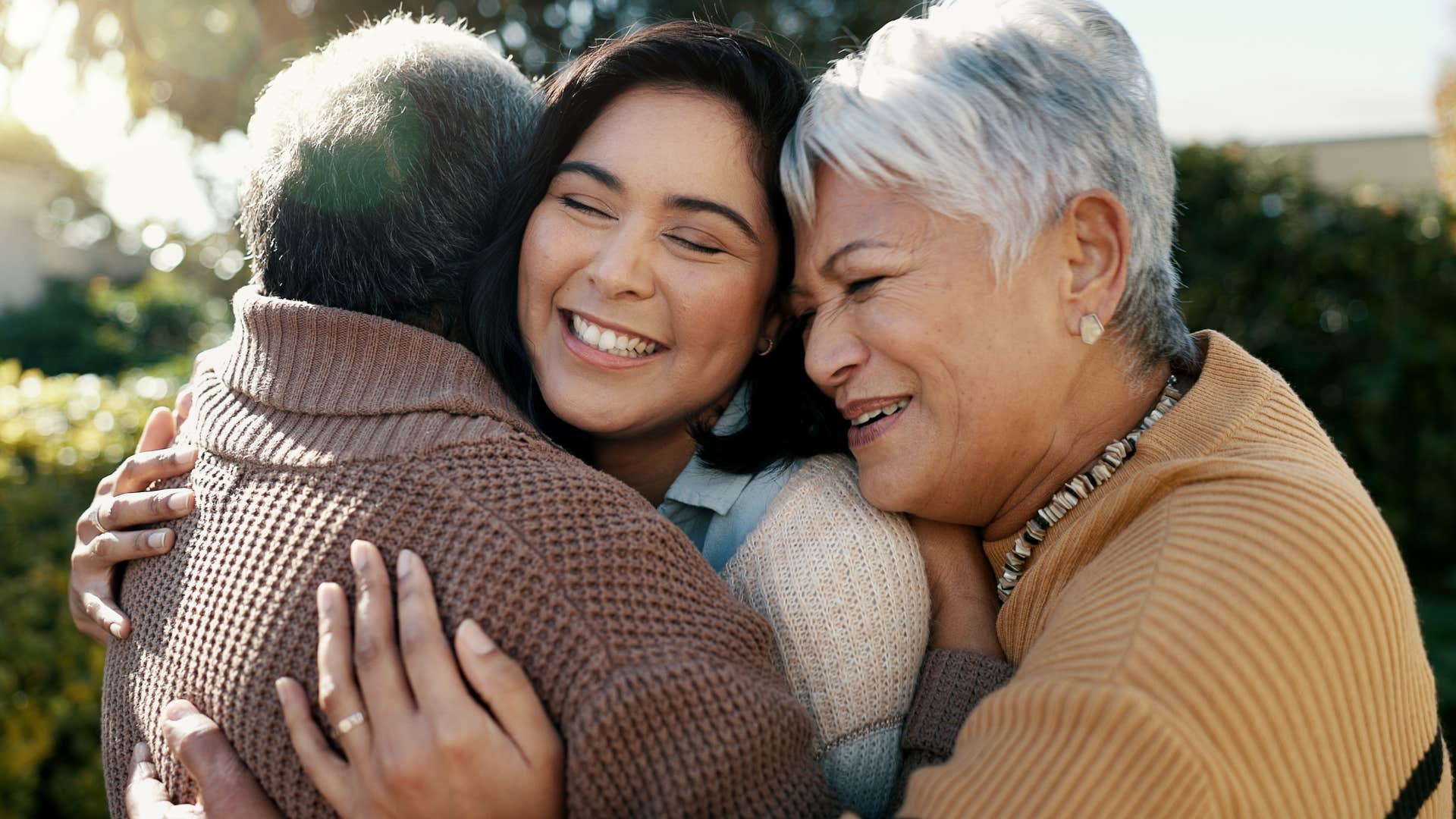 two grandparents hugging their adult granddaughter