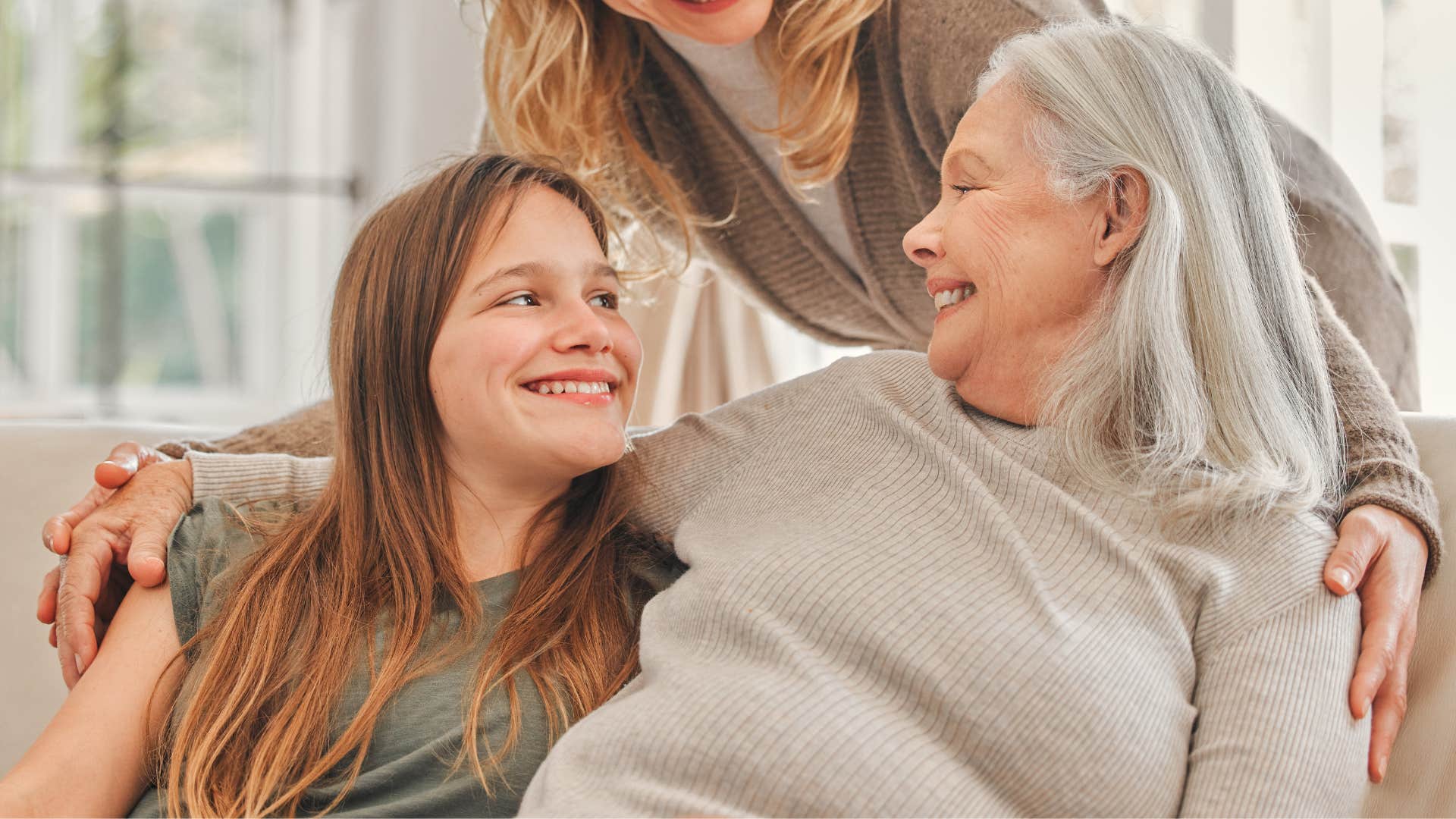 grandmother smiling and hugging her daughter and granddaughter