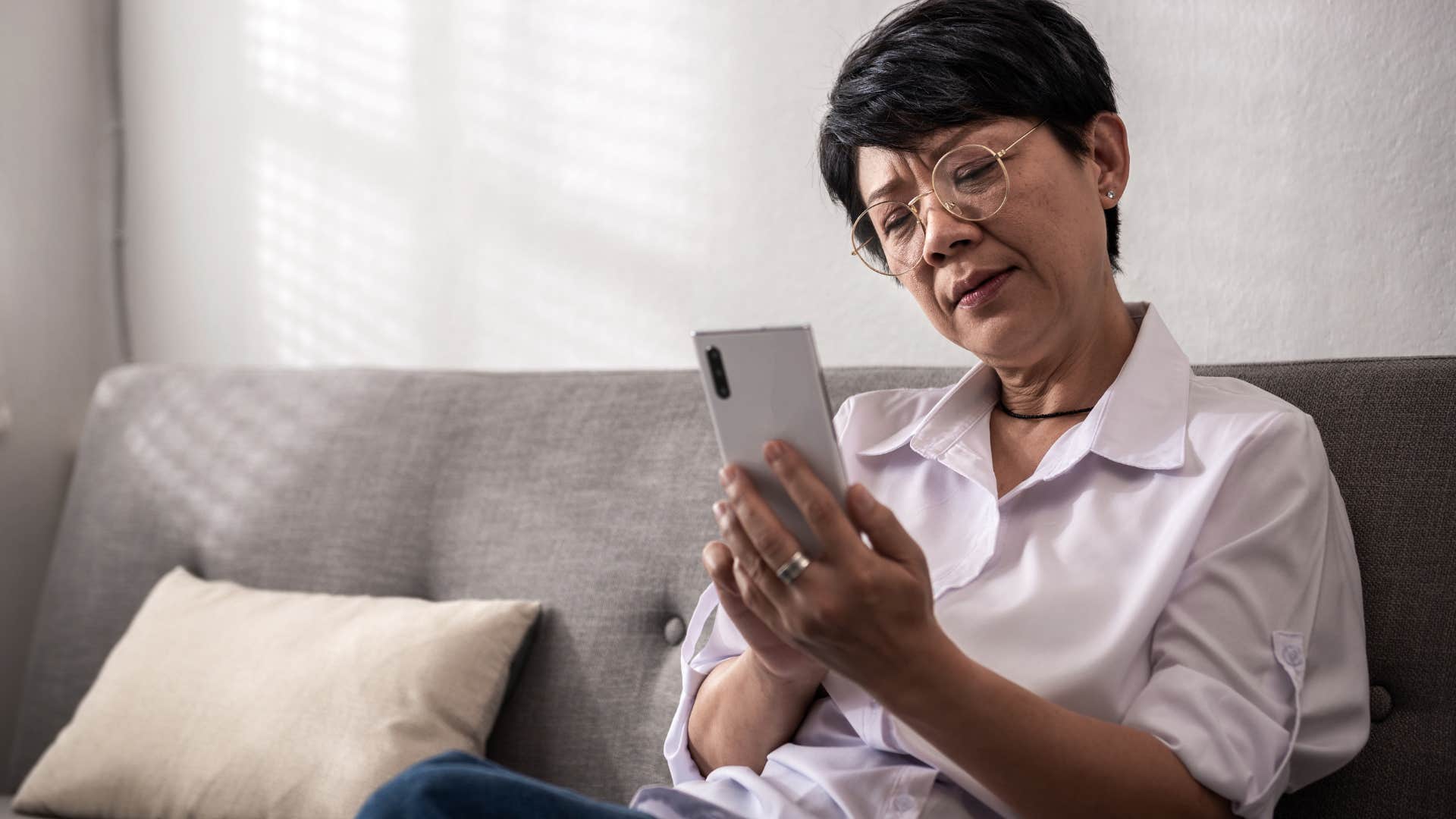 Annoyed boomer woman looking at her phone