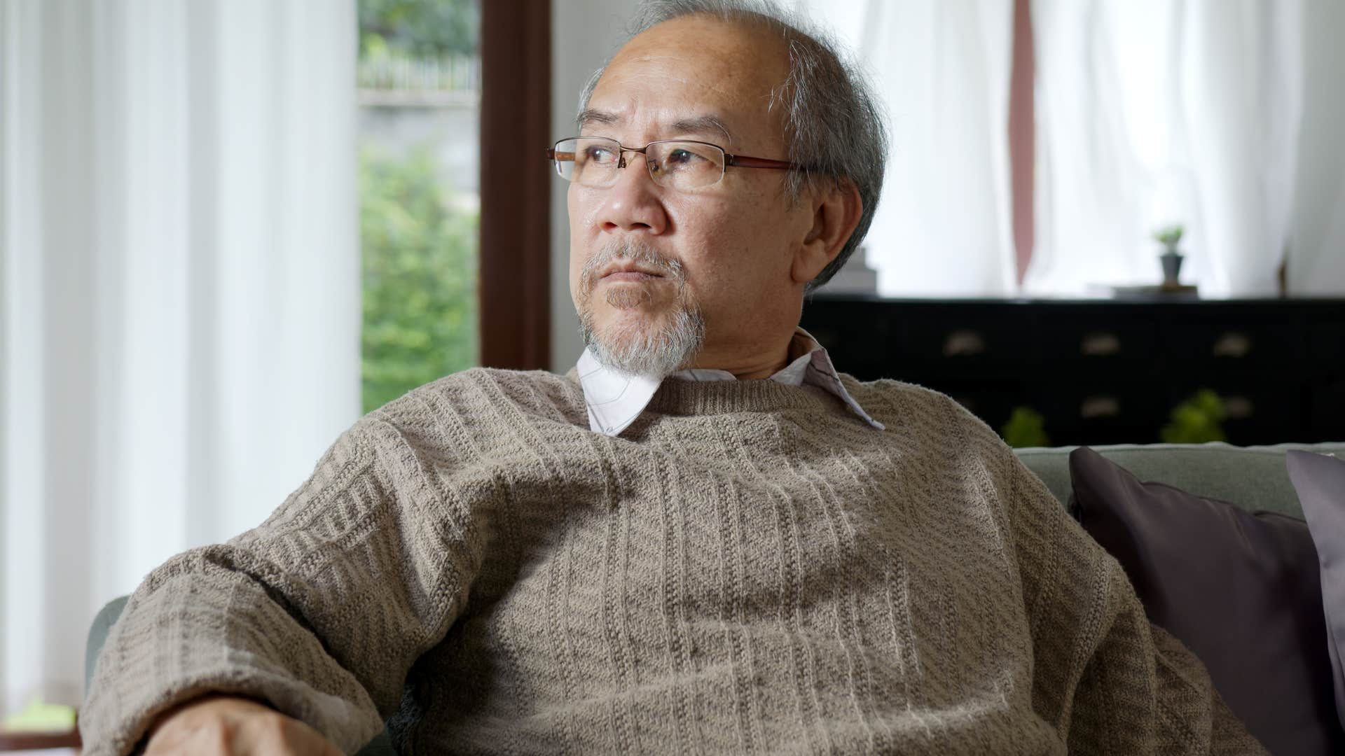 Annoyed boomer man sitting on his couch