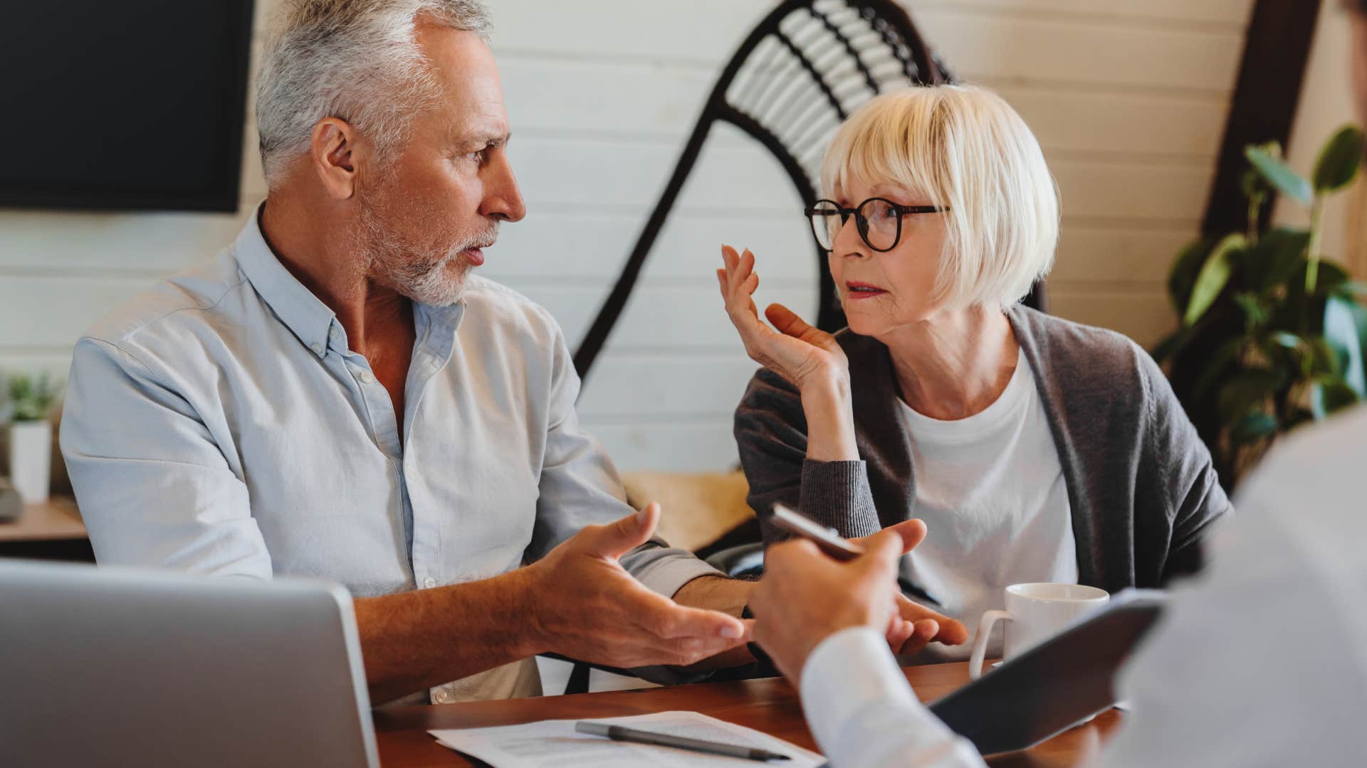 Older couple arguing with each other at a man's desk