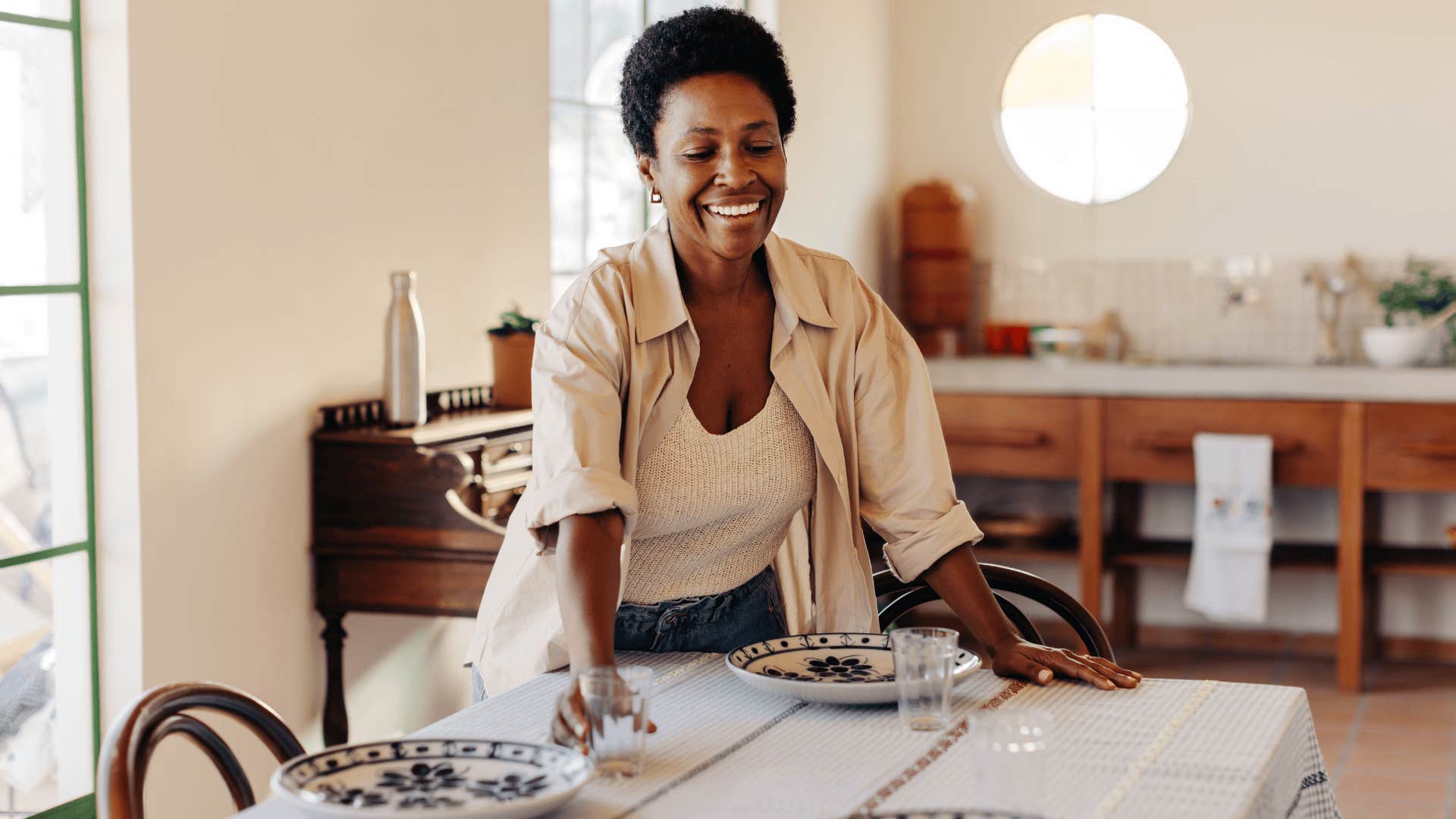 Boomer woman smiling and setting the table with fine china