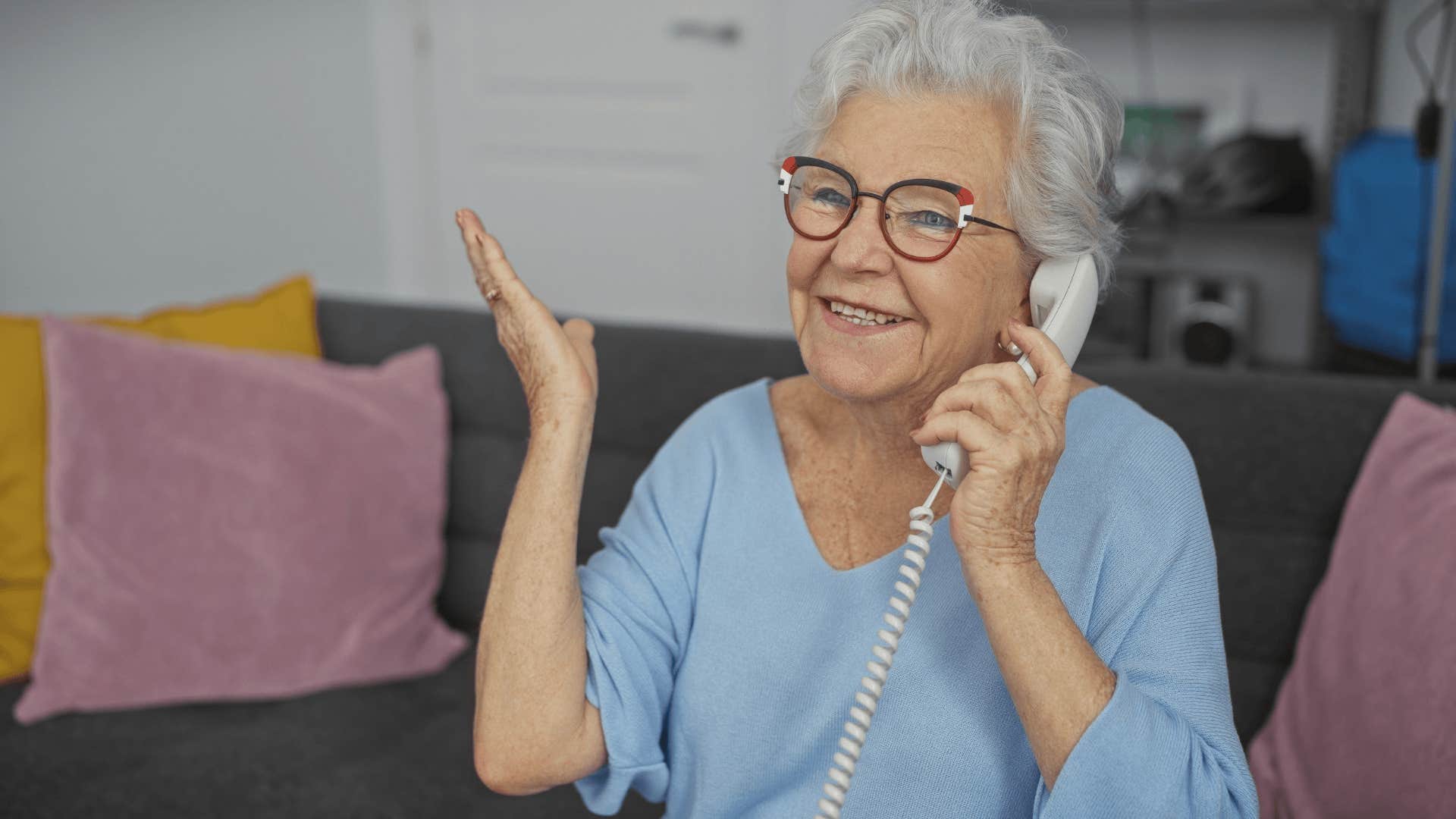 boomer woman smiling and talking on a landline phone