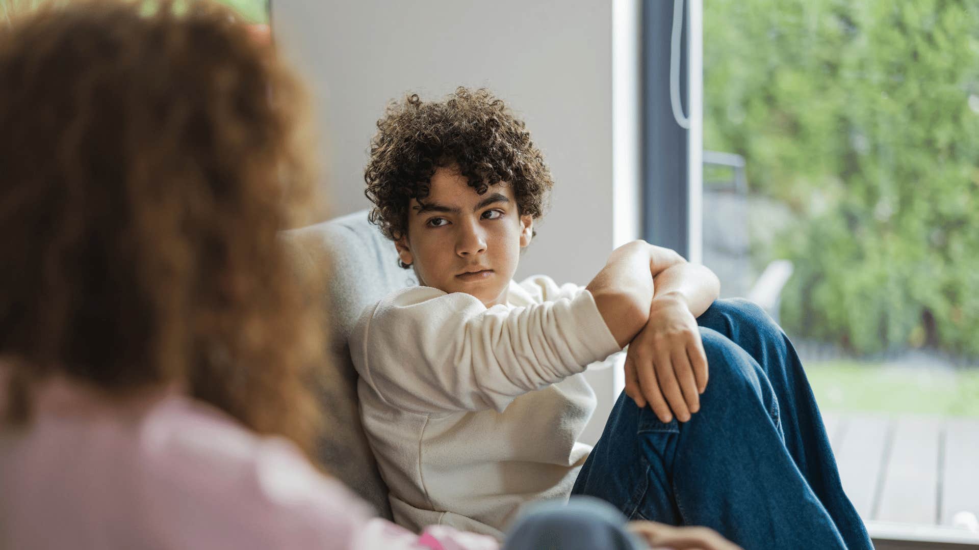 Conflicted teenager with defensive body language talks to parent