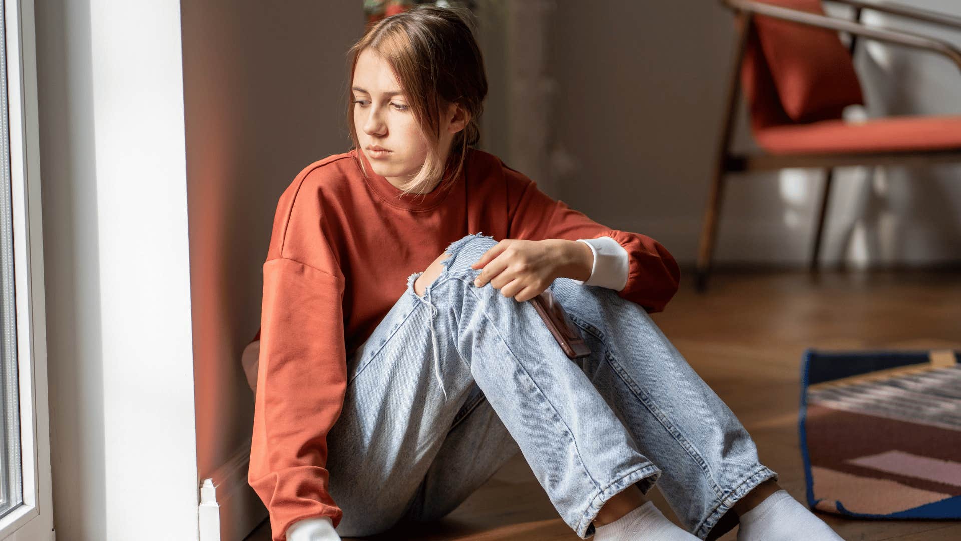 Teenager sits on floor and regulates their emotions