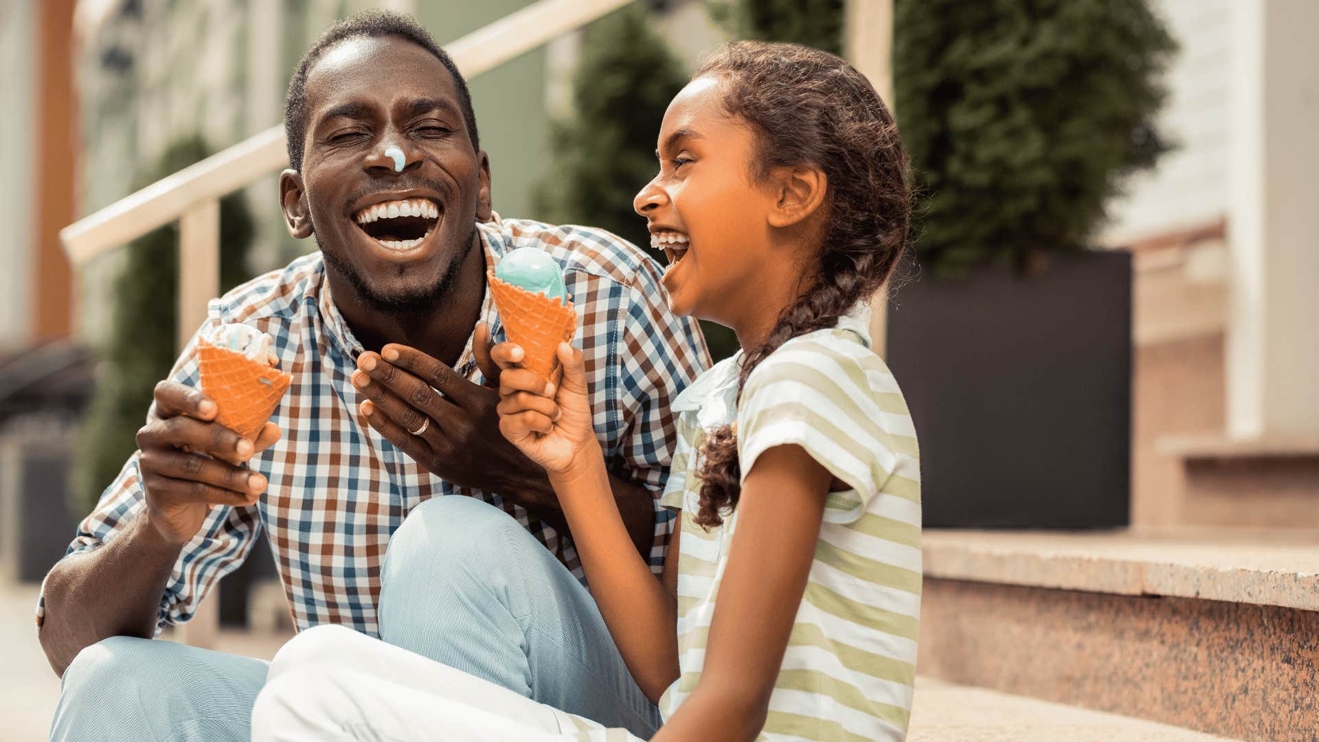 Man and girl laugh while sharing ice cream