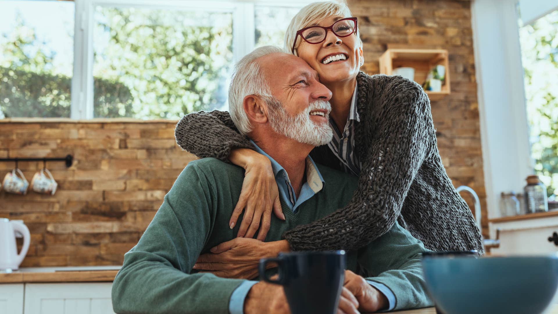 older couple smiling and hugging in their kitchen