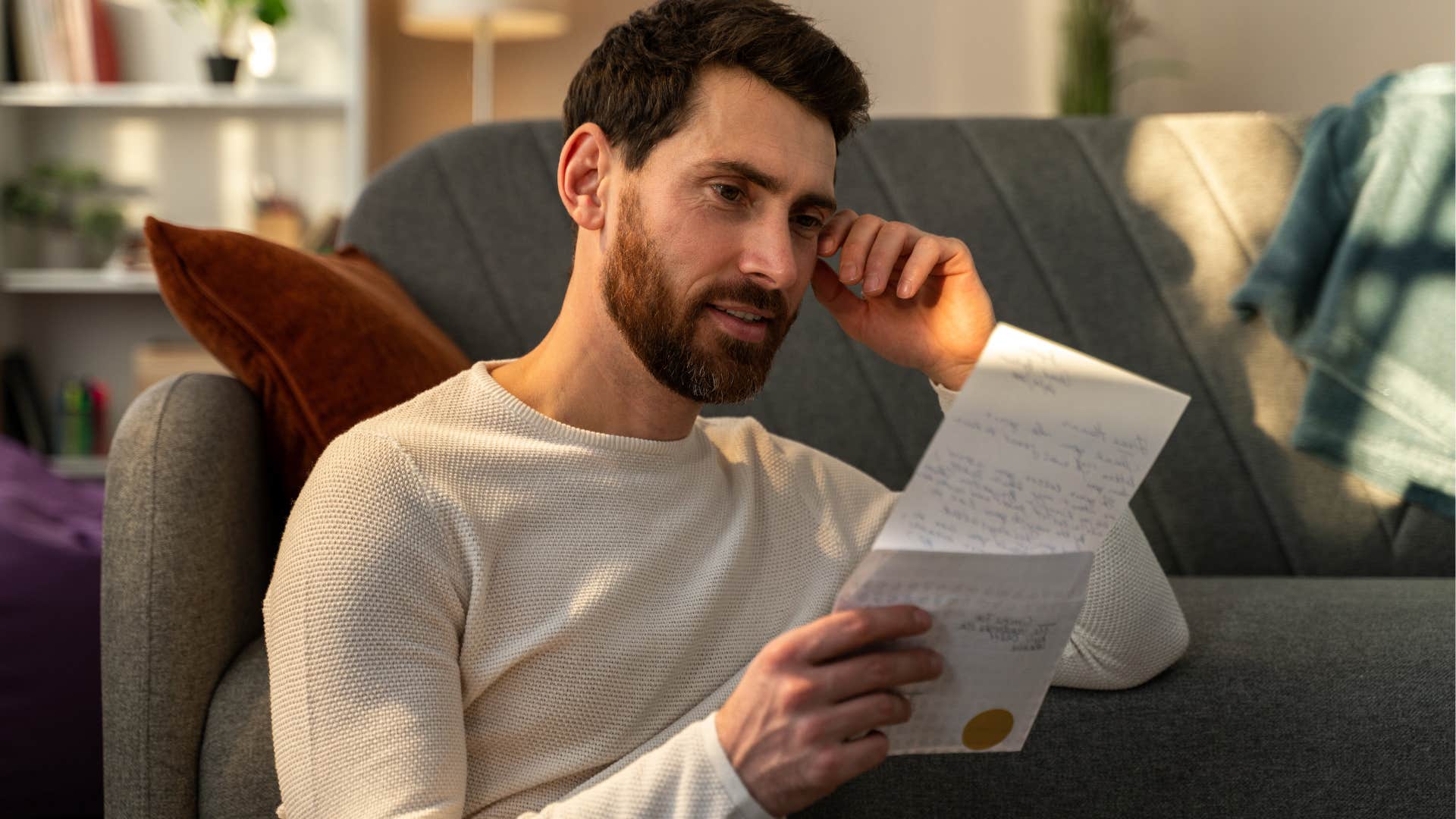 young man smiling and reading a letter