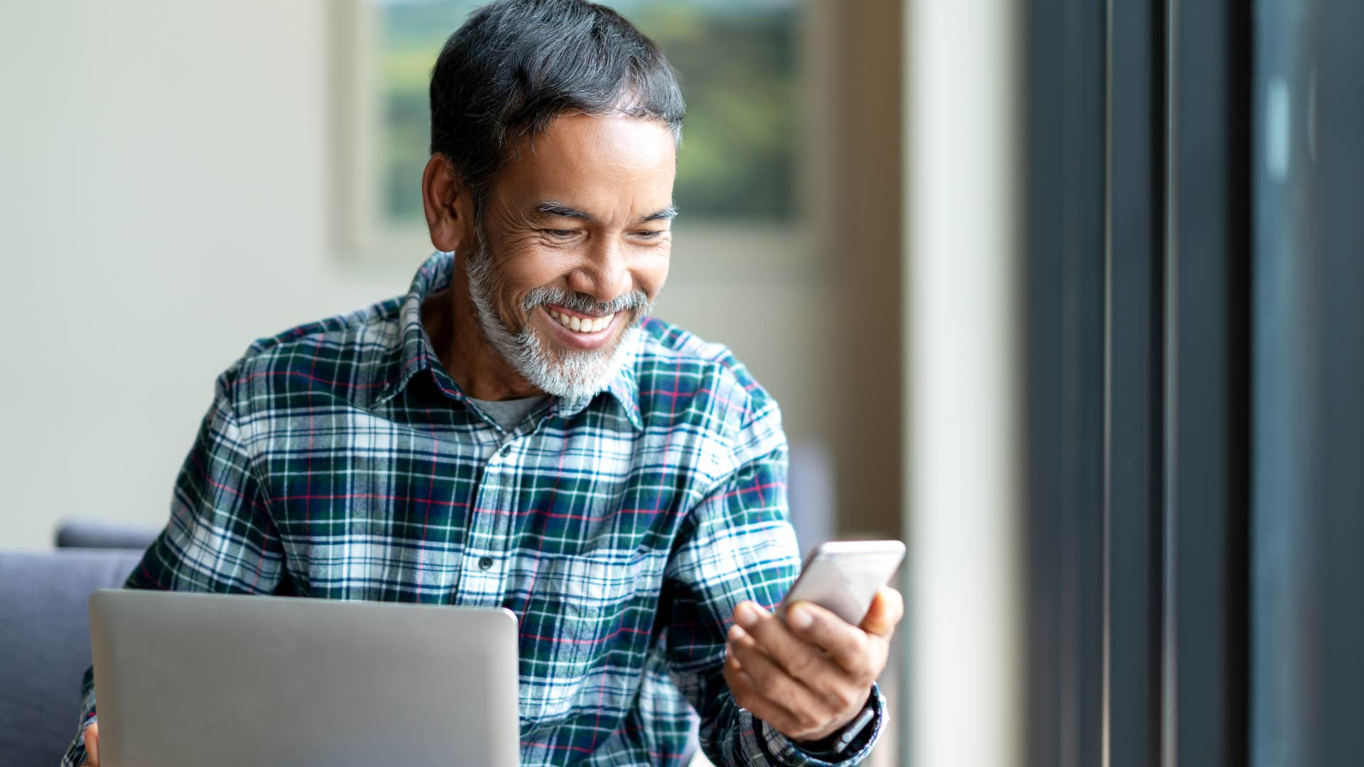 older man smiling and looking at his phone