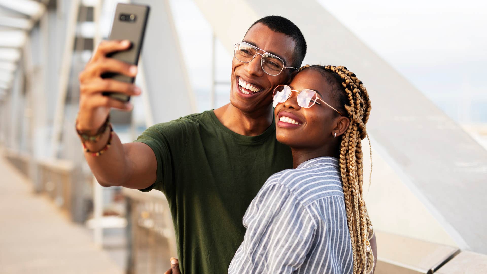 Gen Z couple smiling and taking a photo to post on social media