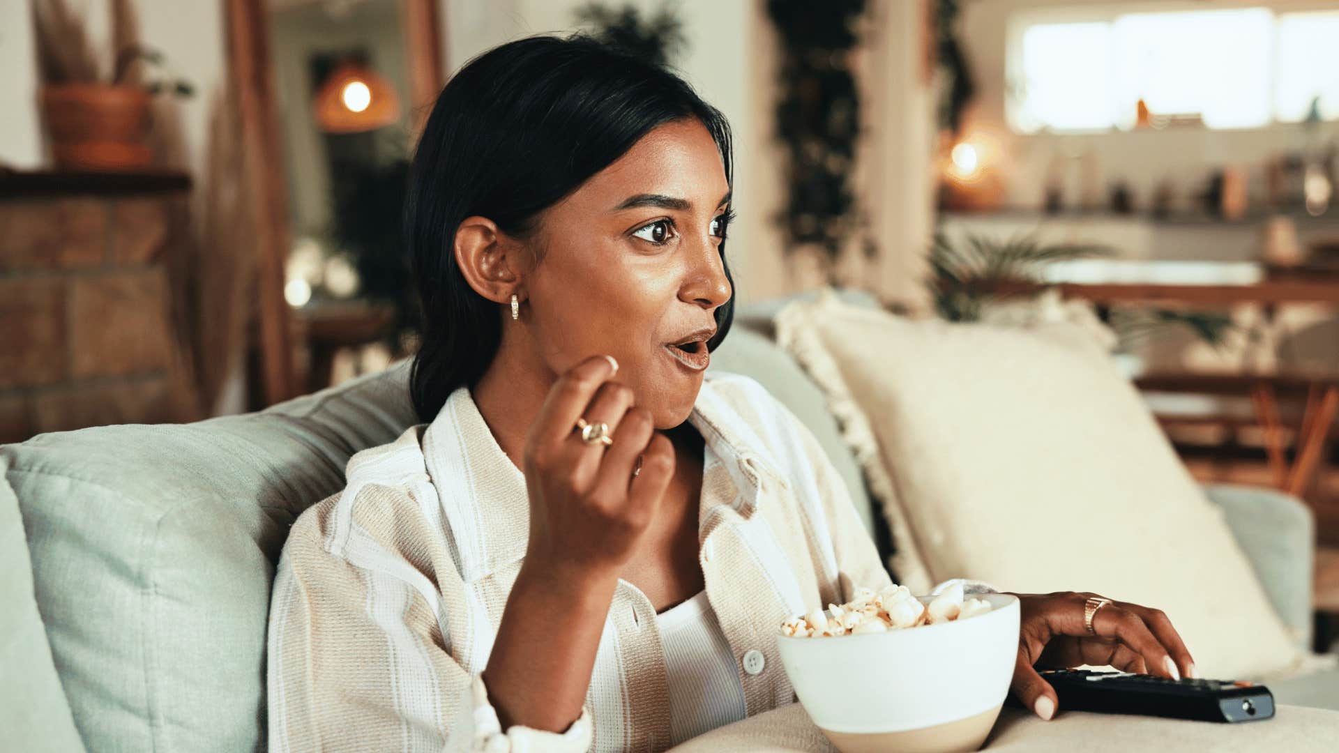 Excited woman watches TV alone