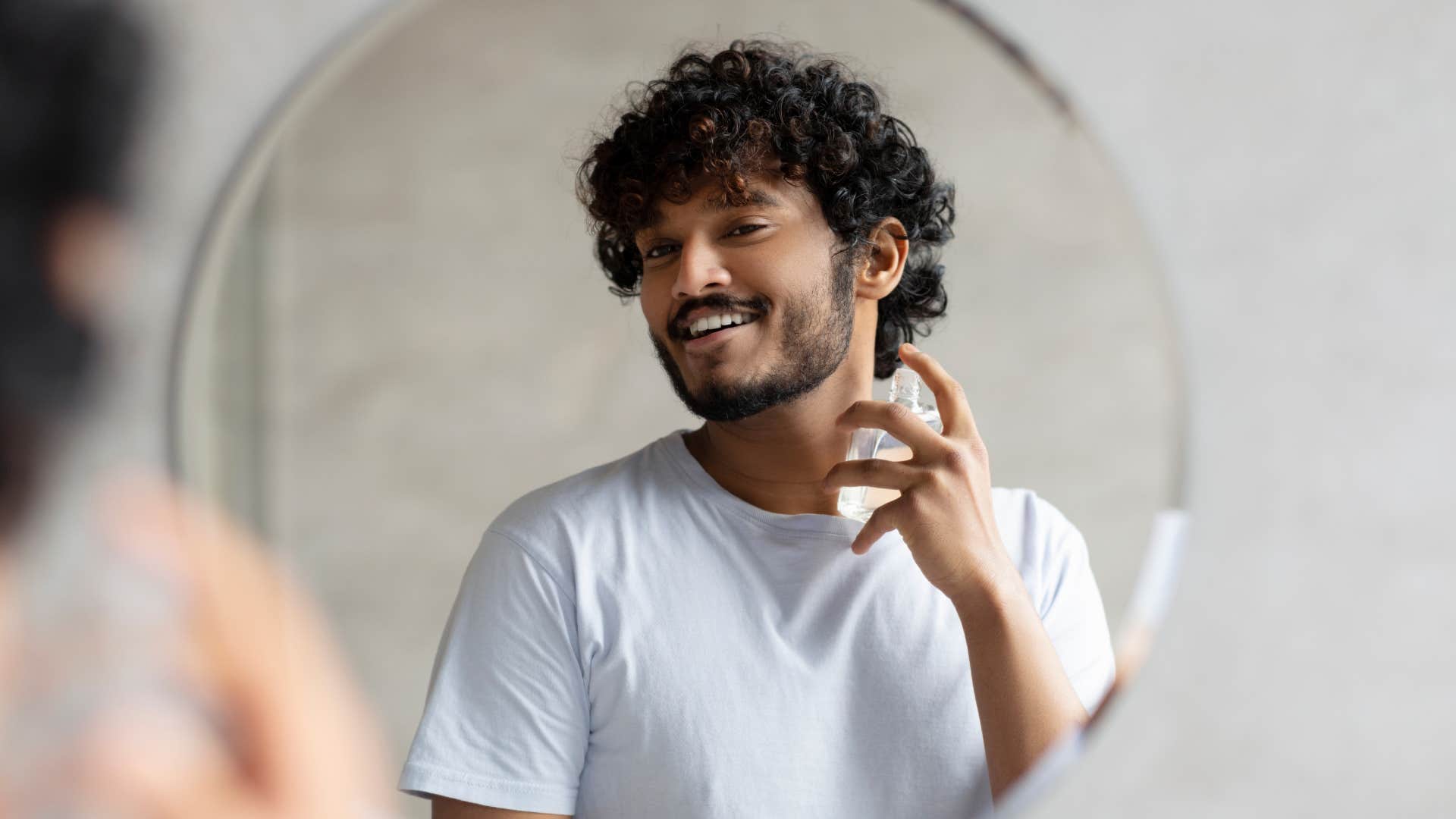 man spraying cologne in mirror