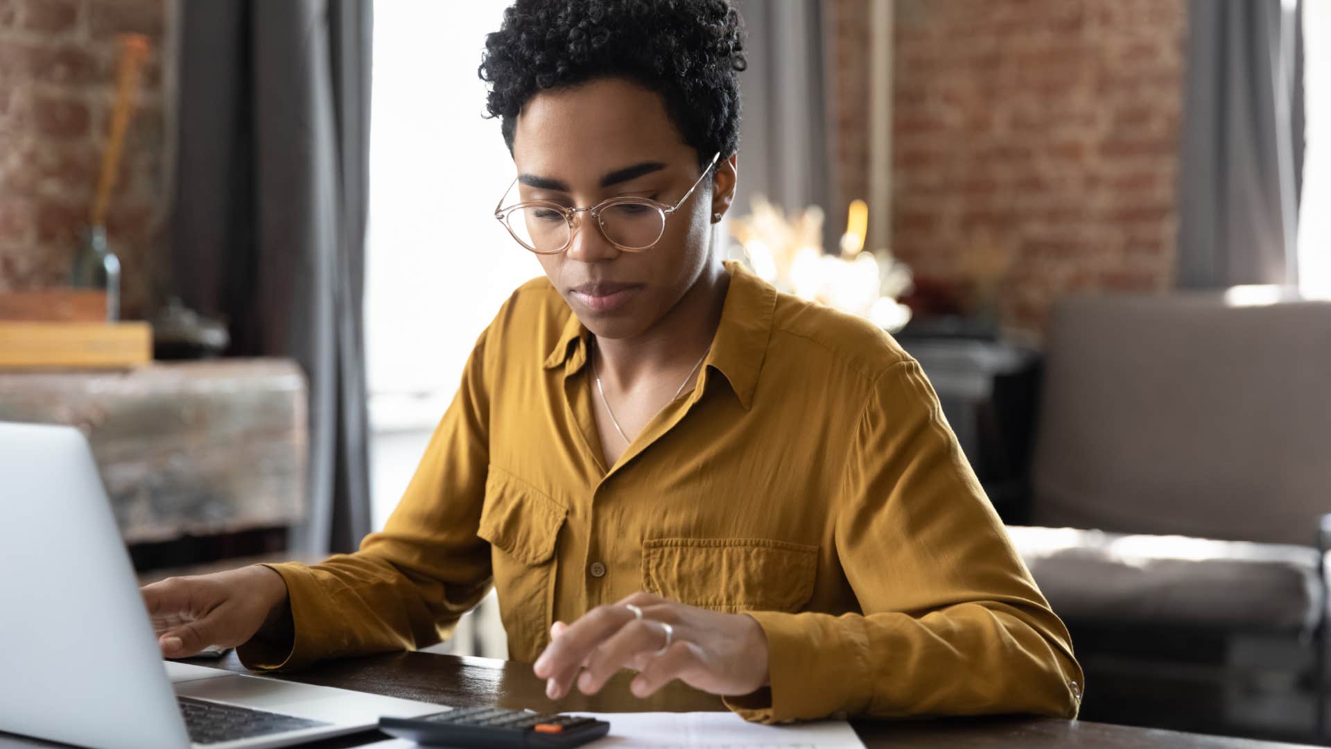 middle-class woman budgeting her finances on laptop and calculator