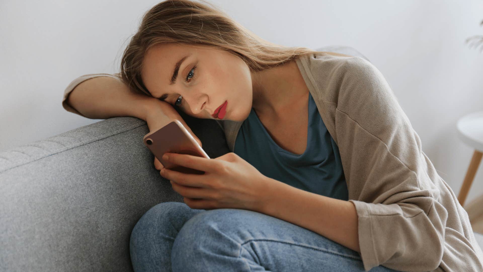 sad woman looking at breakup text on her phone