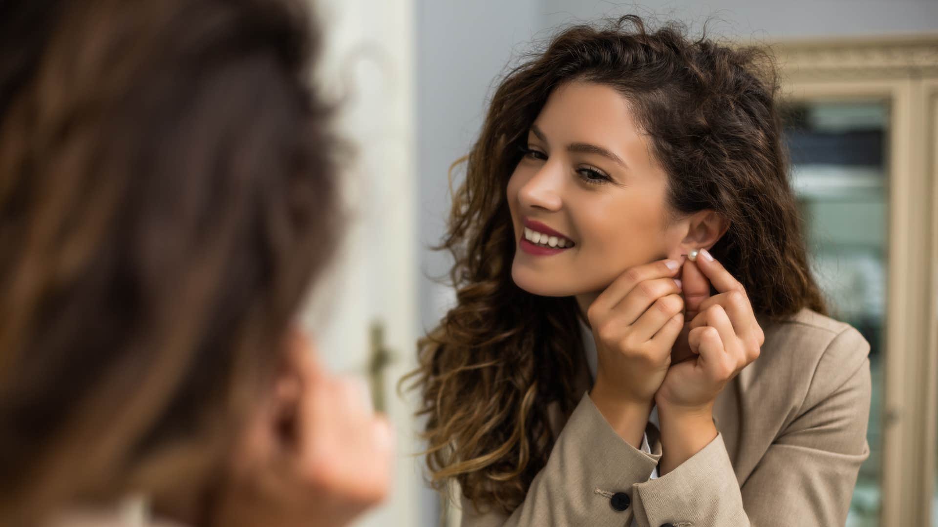 woman putting on earrings 