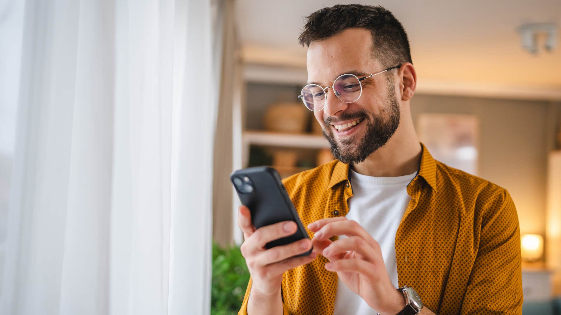 man smiling and texting on his phone