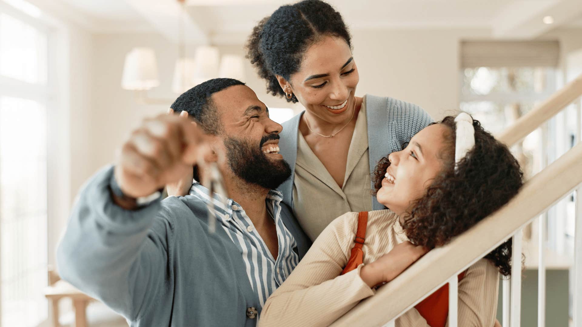 Happy family hold up keys to their new home