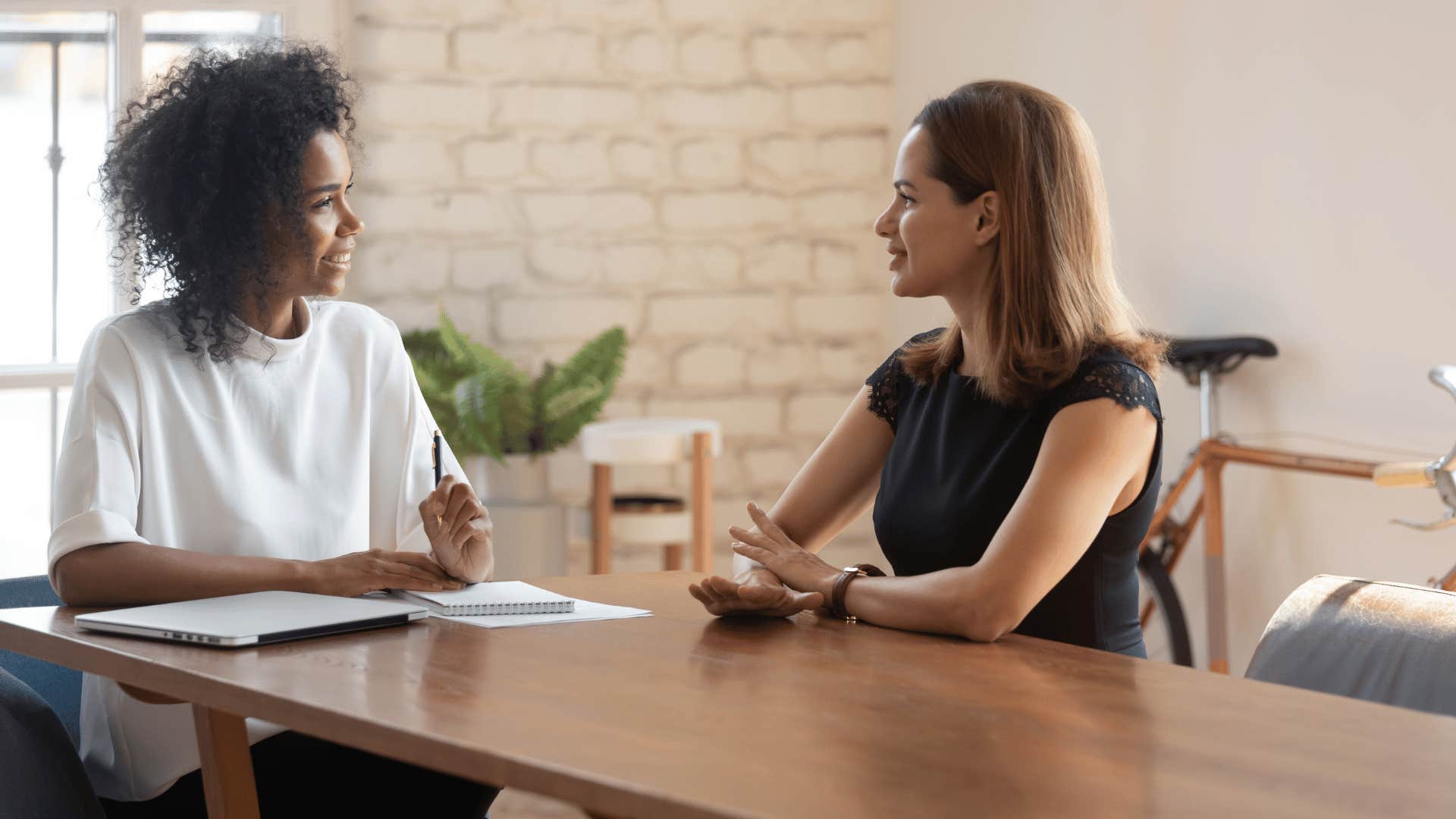 women talking next to each other at table