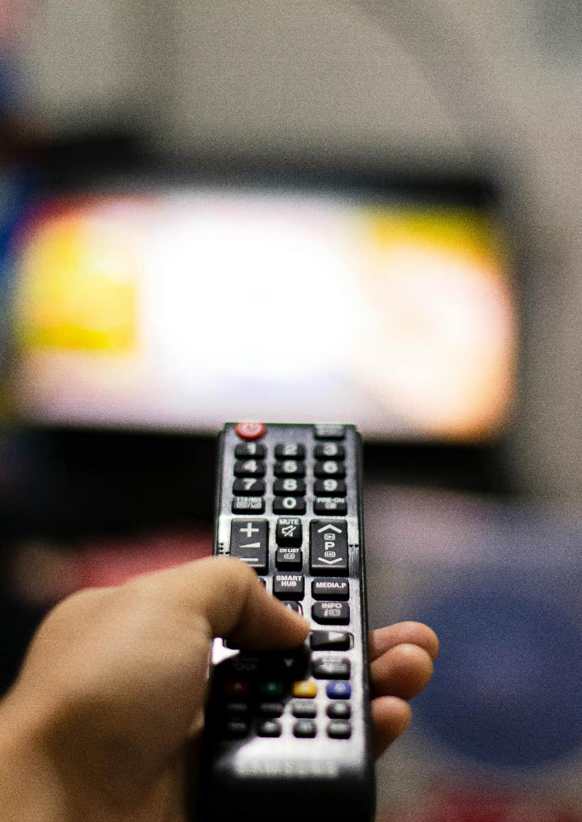 person holding tv remote watching subscription streaming service