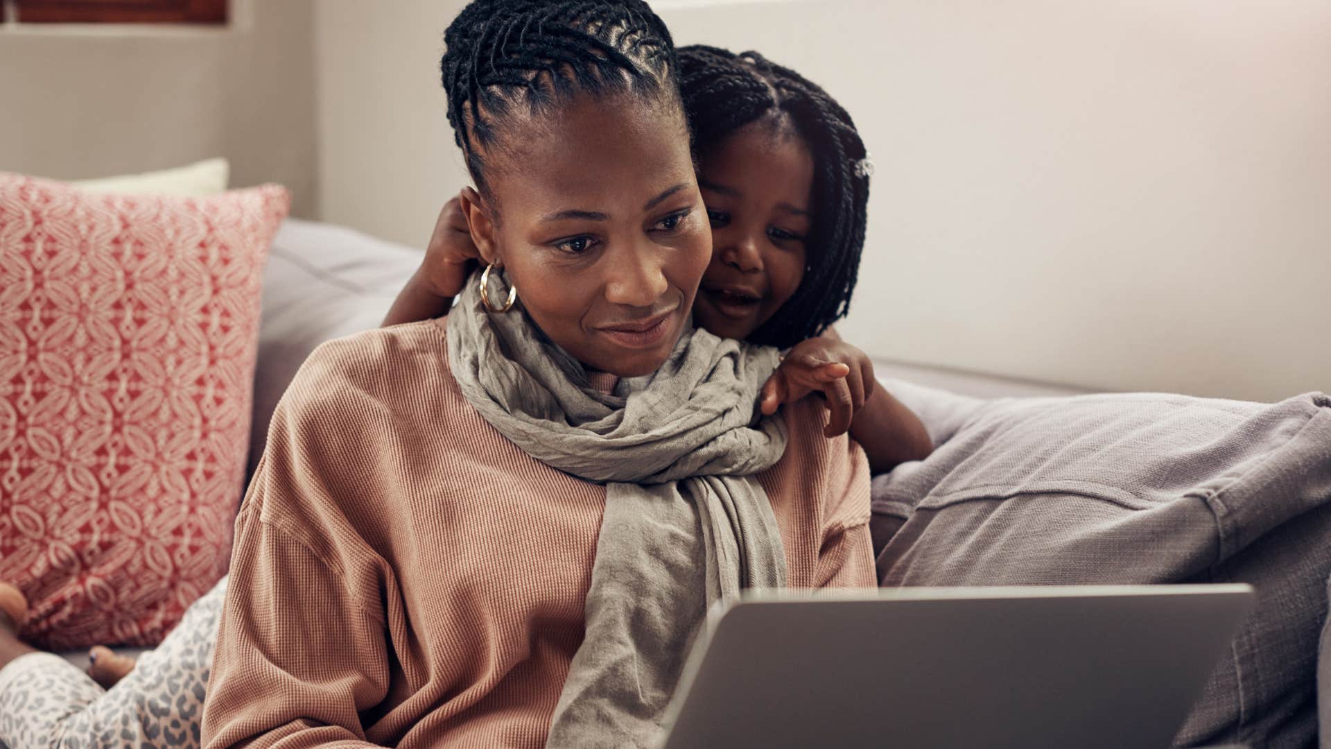 Woman working on her laptop while caring for her daughter