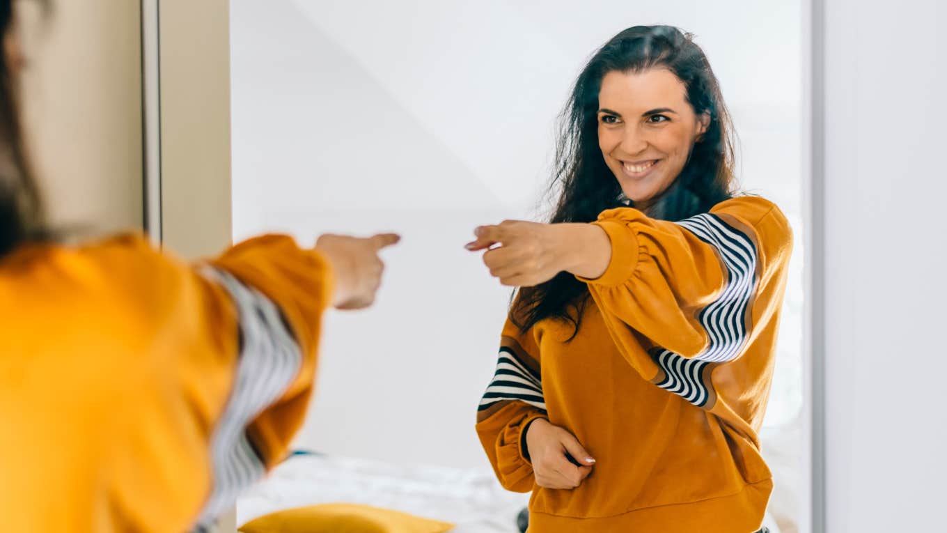 motivated woman pointing finger at reflection in mirror 