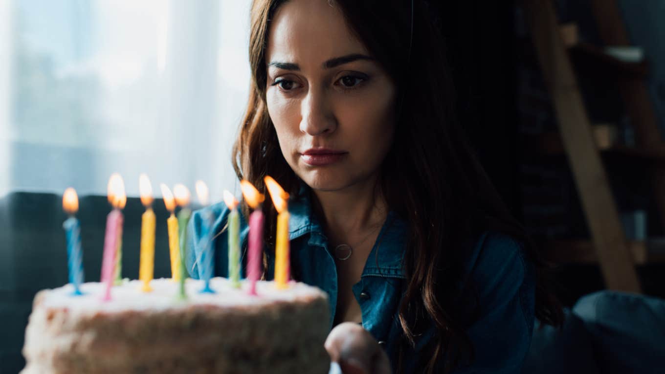 sad woman looking at birthday cake 