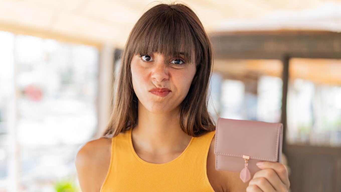 Phrases That Only Make Sense If You Were Raised By Broke Parents frugal woman holding purse after being raised by broke parents