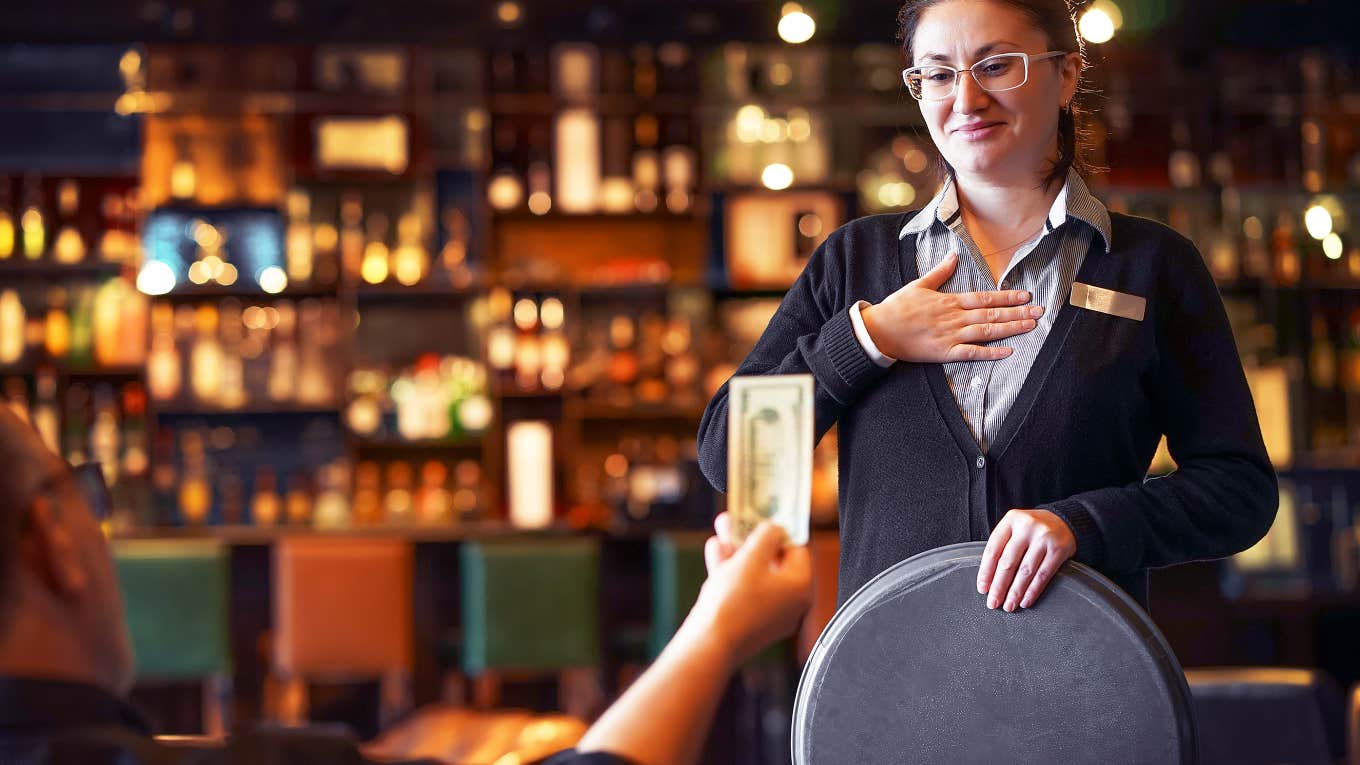 man handing tip to server in restaurant