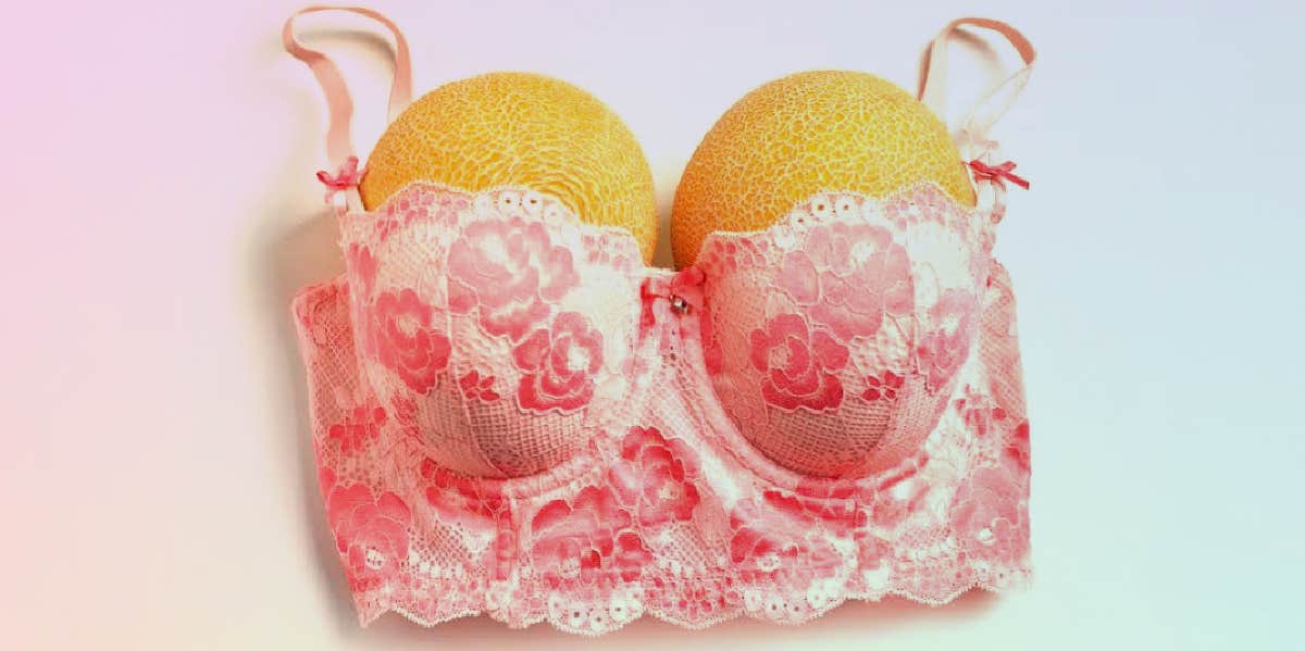 Foto de Woman small boobs puts big fruit in her bra do Stock